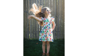 Girl in ruffle sleeve dress in colorful veggie print dress