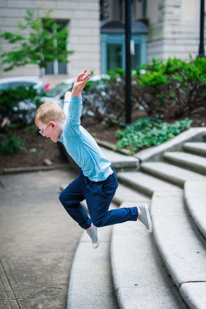 Unique Kids Clothes by Worthy Threads clothing brand.  Boy in blue raglan jumping off stairs.  Sibling coordinating outfits available