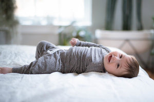 Unique Baby Clothes and sibling coordinating outfits.  Baby in grey set laying on bed