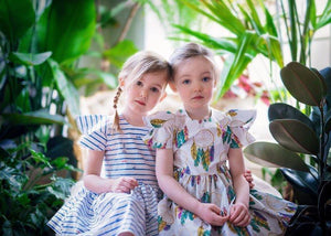 Unique kids clothes.  Two girls wearing vintage style dresses surrounded by plants. Coordinating sibling outfits available