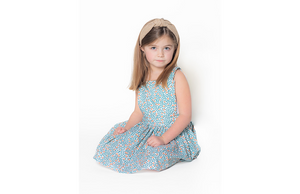 Toddler girl modeling pinafore dress in orange grove print
