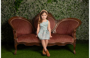 Model in girls pinafore dress sitting on couch