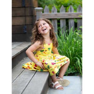 Girl laughing in yellow sundress with veggie print