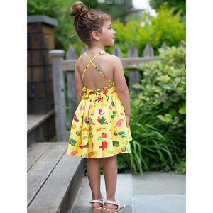 Back view of toddler in tie back veggie print dress