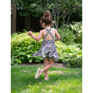 Toddler girl modeling cross back twirly dress in neon leopard, back view