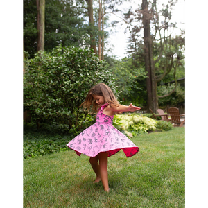 Girl twirling in hot pink dinosaur dress with racer back