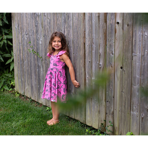 Toddler in girls hot pink twirly dress with dinosaur print