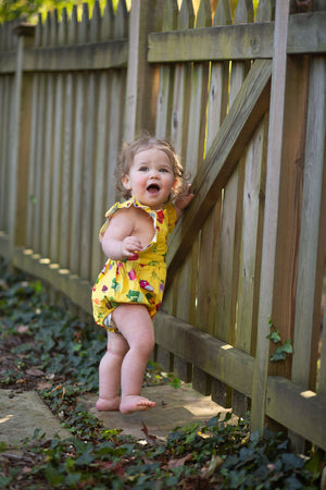 Baby modeling bubble romper in Farmer’s Market print