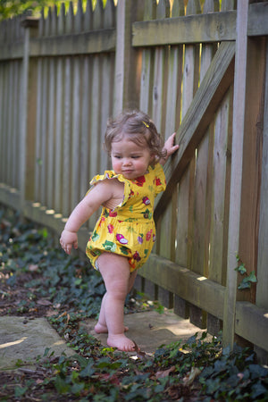 Baby bubble romper in yellow veggie print on model