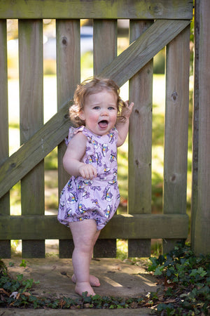 Baby modeling purple bubble romper in roller skates print