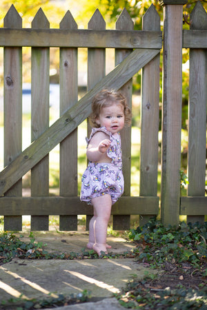 Baby modeling purple bubble romper in roller skates print