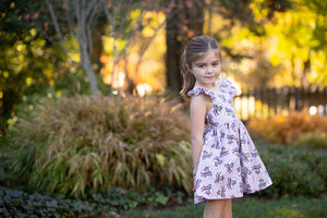 Model in purple girls ruffle sleeve dress in retro roller skates print