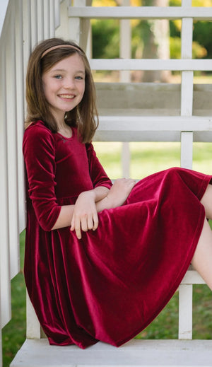 Model in girls christmas holiday twirly dress in burgundy velvet 
