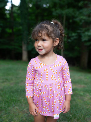 Toddler in Christmas holiday bubble romper featuring pink candy cane print