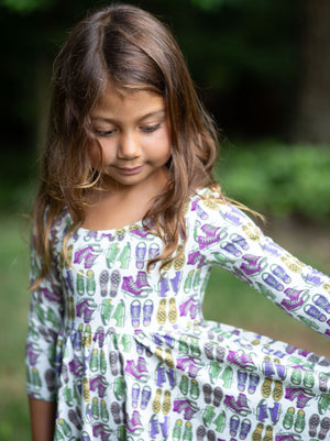 Toddler wearing girls twirly dress in retro funky sneakers print Holding out skirt