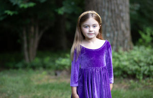 Toddler wearing girls twirly dress in eggplant purple stretch velvet, close up view
