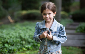 Toddler modeling girls puff sleeve denim jacket over pinafore dress, close up view