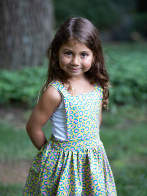 Toddler modeling girls pinafore dress in cheetah print, close up view
