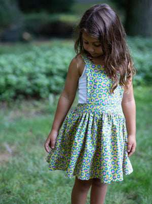 Toddler modeling girls pinafore dress in cheetah print, close up view