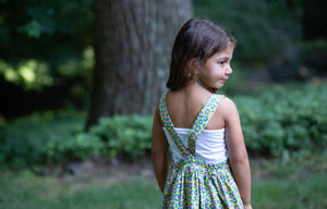 Toddler modeling girls pinafore dress in cheetah print, back view