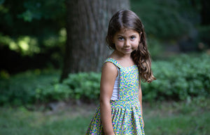 Toddler modeling girls pinafore dress in cheetah print, side view