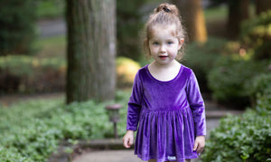 Toddler wearing baby bubble romper in eggplant purple stretch velvet