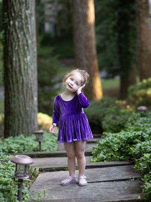 Toddler wearing baby bubble romper in eggplant purple stretch velvet, front view