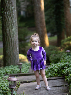 Toddler modeling baby bubble romper in eggplant purple stretch velvet