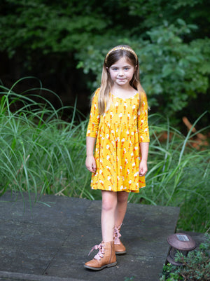 Model wearing girls twirly Christmas holiday dress in Santa print