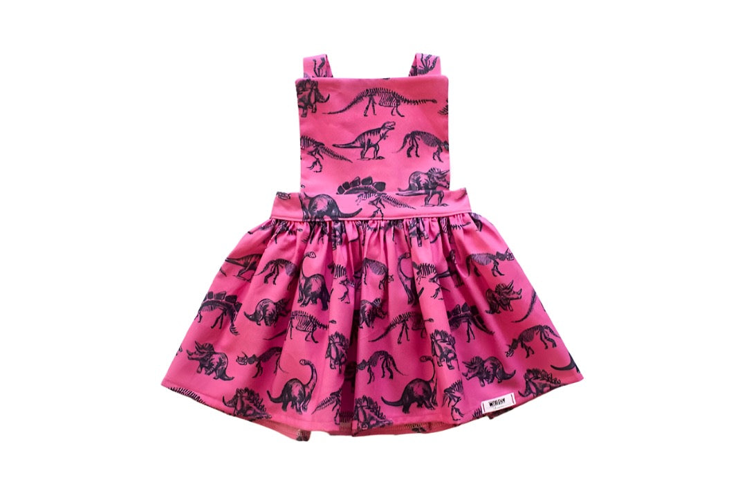 Dinosaur dress girl.  Magenta pink girls pinafore dress with dinosaur print available in matching sister outfits newborn and toddler.