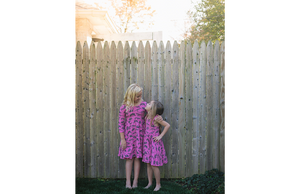 Sister wearing matching pink dinosaur dresses: STEM clothing for girls!