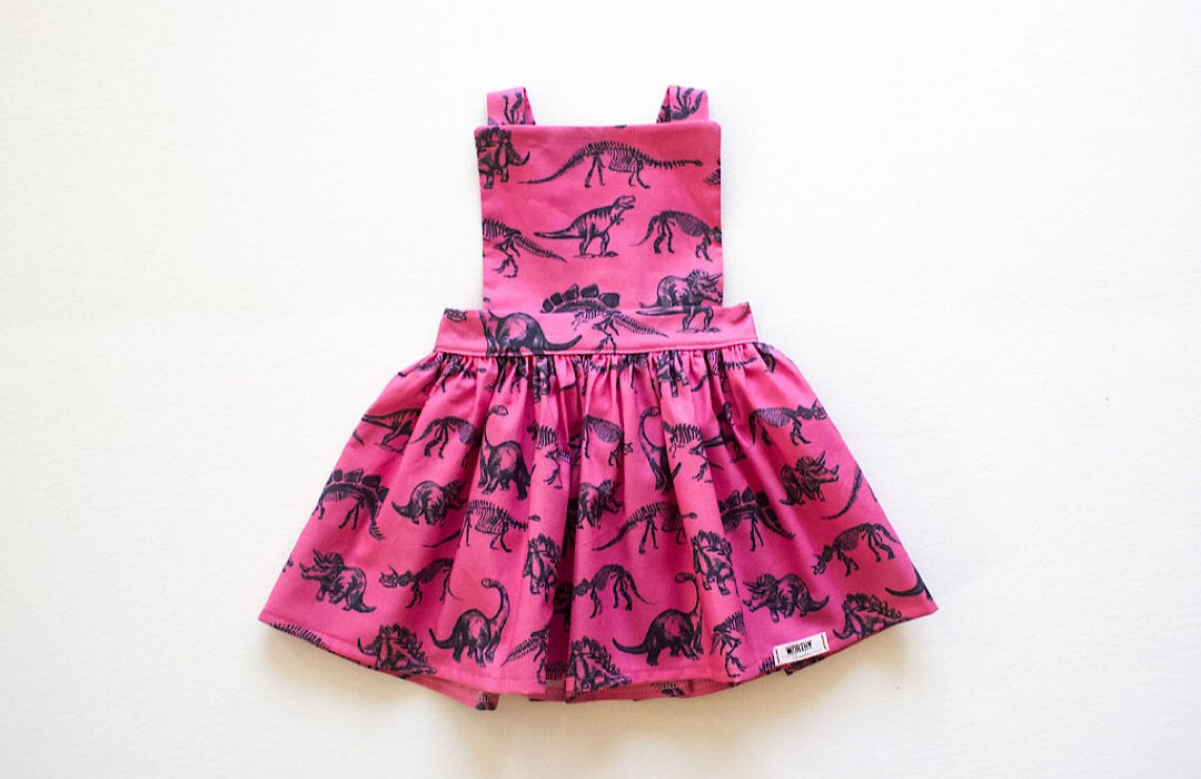 Baby dinosaur dress in bright pink.  Our favorite Toddler & baby Pinafore Dress available in matching sister outfits newborn and toddler.