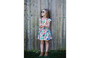 Girl modeling ruffle sleeve dress in colorful veggie print
